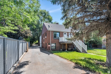 View of front of property with brick siding, a shingled roof, and stairway