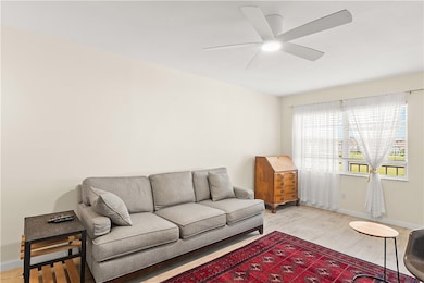 Living area with light wood-style floors and a ceiling fan