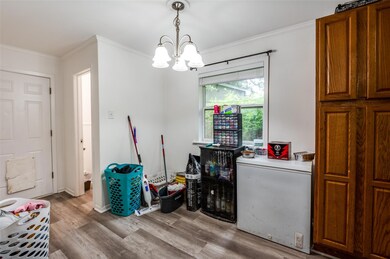 Miscellaneous room featuring light wood-type flooring, crown molding, and a notable chandelier