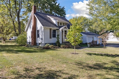 View of front of home featuring a front yard, a chimney, a shingled roof, and a garage