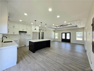 Kitchen with a raised ceiling, a center island, recessed lighting, hanging light fixtures, and decorative backsplash