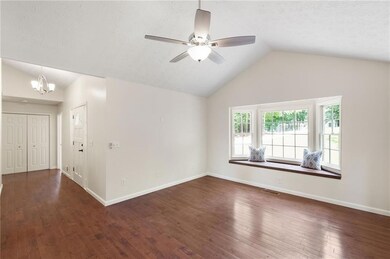 Unfurnished room featuring vaulted ceiling, a ceiling fan, a chandelier, wood finished floors, and a textured ceiling