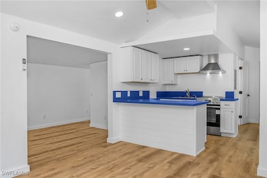 Kitchen featuring wall chimney range hood, white c