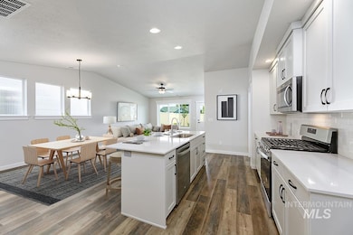 Kitchen with appliances with stainless steel finishes, white cabinets, a center island with sink, open floor plan, and dark wood-style floors