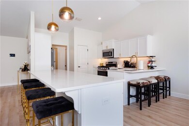 Kitchen with appliances with stainless steel finishes, a peninsula, light wood finished floors, a kitchen bar, and white cabinetry