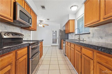 Kitchen with light tile patterned floors, stainless steel appliances, a sink, visible vents, and a ceiling fan