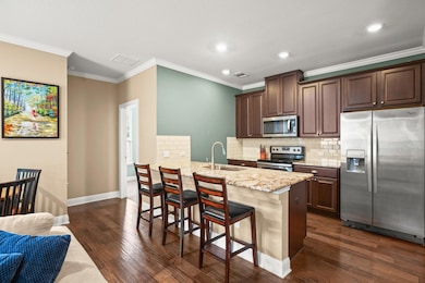 The kitchen is a true highlight, featuring a peninsula breakfast bar, sparkling granite counters, rich cabinetry, a tile backsplash, a built-in microwave, a smooth cooktop, and stainless steel appliances.