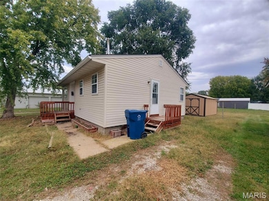 Back of house with a lawn, a deck, and a shed