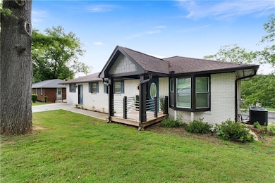Single story home featuring brick siding, a front yard, roof with shingles, and central air condition unit