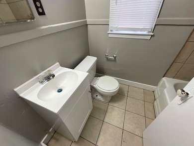 Full bath featuring baseboards, toilet, tile patte