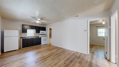 Kitchen with white appliances, a textured ceiling,