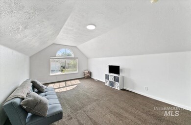 Living area featuring a textured ceiling, vaulted ceiling, and carpet flooring