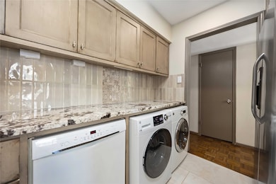 Convenient laundry nook located off the kitchen, accommodating a full-size washer and dryer with granite folding counter, under-cabinet lighting and built-in storage.