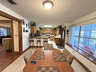 Dining space with healthy amount of natural light, light tile patterned floors, and a textured ceiling