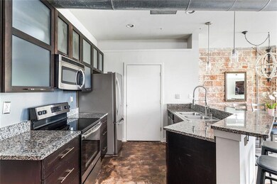 Kitchen with appliances with stainless steel finishes, a sink, a peninsula, a kitchen bar, and glass insert cabinets