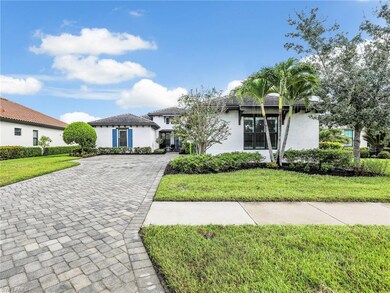 View of front facade featuring a front lawn, stucco siding, and decorative driveway