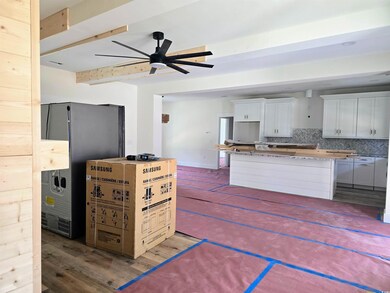 Kitchen featuring a ceiling fan, tasteful backsplash, a center island, wood finished floors, and beam ceiling