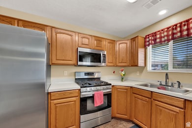 Kitchen with stainless steel appliances, light countertops, brown cabinets, and a textured ceiling