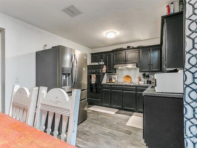 Kitchen featuring appliances with stainless steel finishes, light wood-type flooring, under cabinet range hood, dark cabinets, and a warming drawer