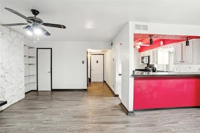 Kitchen featuring a ceiling fan, dark countertops, light wood-type flooring, and black appliances
