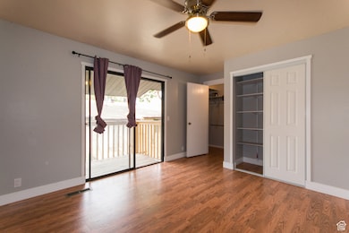 Unfurnished bedroom featuring wood finished floors, access to outside, and ceiling fan