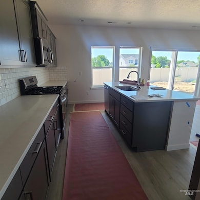 Kitchen featuring appliances with stainless steel finishes, a textured ceiling, plenty of natural light, a center island with sink, and tasteful backsplash