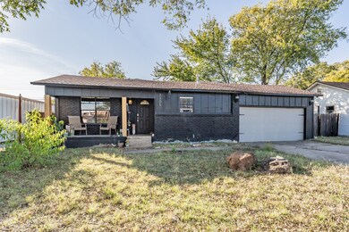 Single story home with brick siding, board and batten siding, an attached garage, and driveway