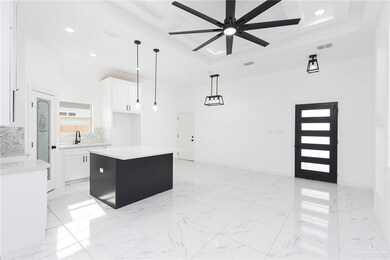 Kitchen featuring white cabinets, pendant lighting, backsplash, a kitchen island, and ceiling fan