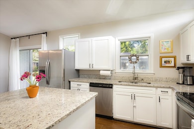 Kitchen featuring stainless steel appliances, a sink, white cabinets, and dark wood-style floors