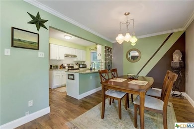 Dining space with ornamental molding and dark wood finished floors