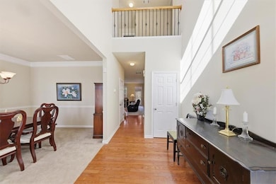 Entrance foyer with light wood-style flooring, a high ceiling, a chandelier, light carpet, and ornamental molding