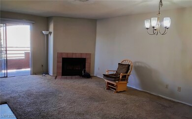 Living area with carpet flooring, a tile fireplace, and a chandelier