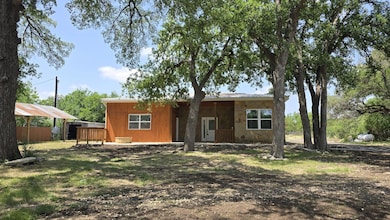 Rear view of house featuring stone siding and fen
