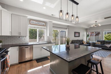 Kitchen featuring hanging light fixtures, dark stone countertops, tasteful backsplash, a kitchen breakfast bar, and white cabinets