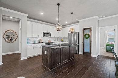Kitchen with backsplash, dark brown cabinets, white cabinetry, stainless steel appliances, and crown molding