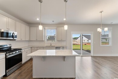 Kitchen featuring appliances with stainless steel finishes, tasteful backsplash, dark wood-type flooring, light stone counters, and recessed lighting