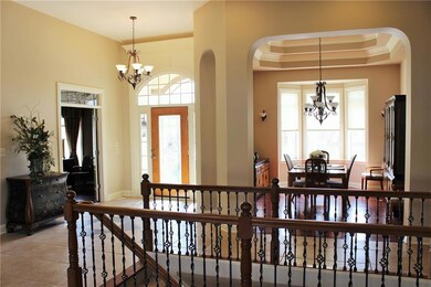 Every room in the home has its' own custom features to brag about.  This is a larger view of the entry showing off the arched openings into the dining room, the beveled glass transom window over the office and the rod iron spindled railing down to the finished basement.
