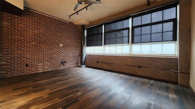 Spare room with brick wall, dark hardwood / wood-s