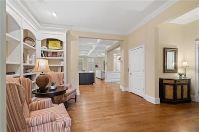 Living area featuring coffered ceiling, wood finished floors, ornamental molding, and beamed ceiling