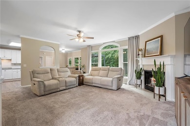 Great room with fireplace, floor to ceiling windows and archway to the kitchen.