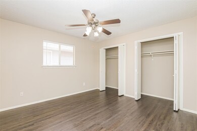 Unfurnished bedroom featuring two closets, a textured ceiling, dark wood-type flooring, and a ceiling fan