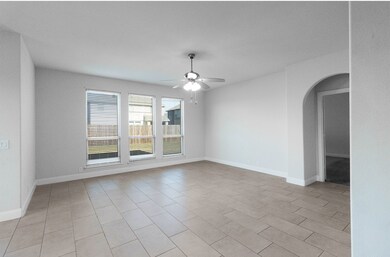 Spare room featuring arched walkways, light tile patterned flooring, and ceiling fan