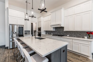 This kitchen is by far any chef’s dream! This spacious kitchen features high ceilings, white stained wood cabinets, quartz countertops, SS appliances, modern tile backsplash, recessed lighting with additional custom pendant lighting, extended counter space, granite kitchen island with sink and space for breakfast bar, and a walk-in pantry all overlooking your huge family room.