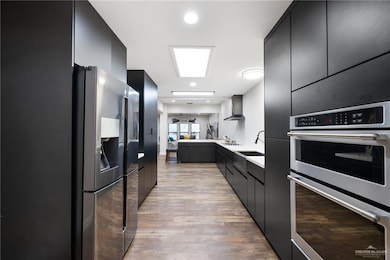 Kitchen with stainless steel double oven, dark cabinets, black fridge, modern cabinets, and recessed lighting
