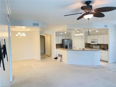 Kitchen featuring backsplash, light carpet, white appliances, white cabinets, and arched walkways