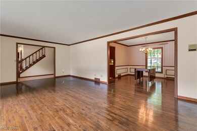 Unfurnished living room with dark hardwood / wood-style floors, a notable chandelier, and crown molding