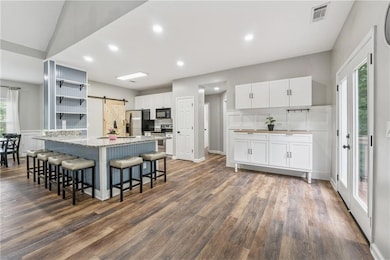 Kitchen featuring a barn door, appliances with stainless steel finishes, open shelves, white cabinets, and recessed lighting