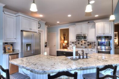 GOURMET KITCHEN AND AMENITIES INCLUDE DOUBLE OVENS, ICE MAKER, WORK ISLAND AND UPGRADED GRANITE