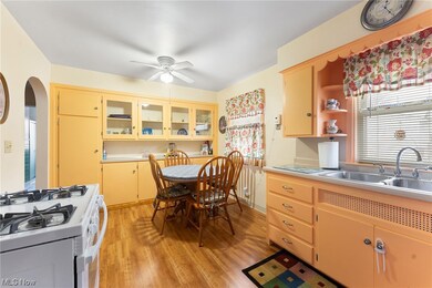 Kitchen with light brown cabinets, light hardwood / wood-style flooring, ceiling fan, white gas range, and sink