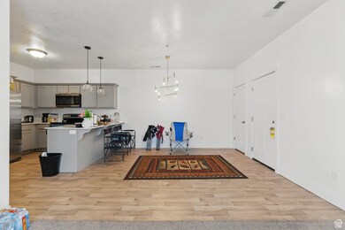 Kitchen featuring gray cabinetry, light countertops, a breakfast bar area, decorative light fixtures, and a peninsula